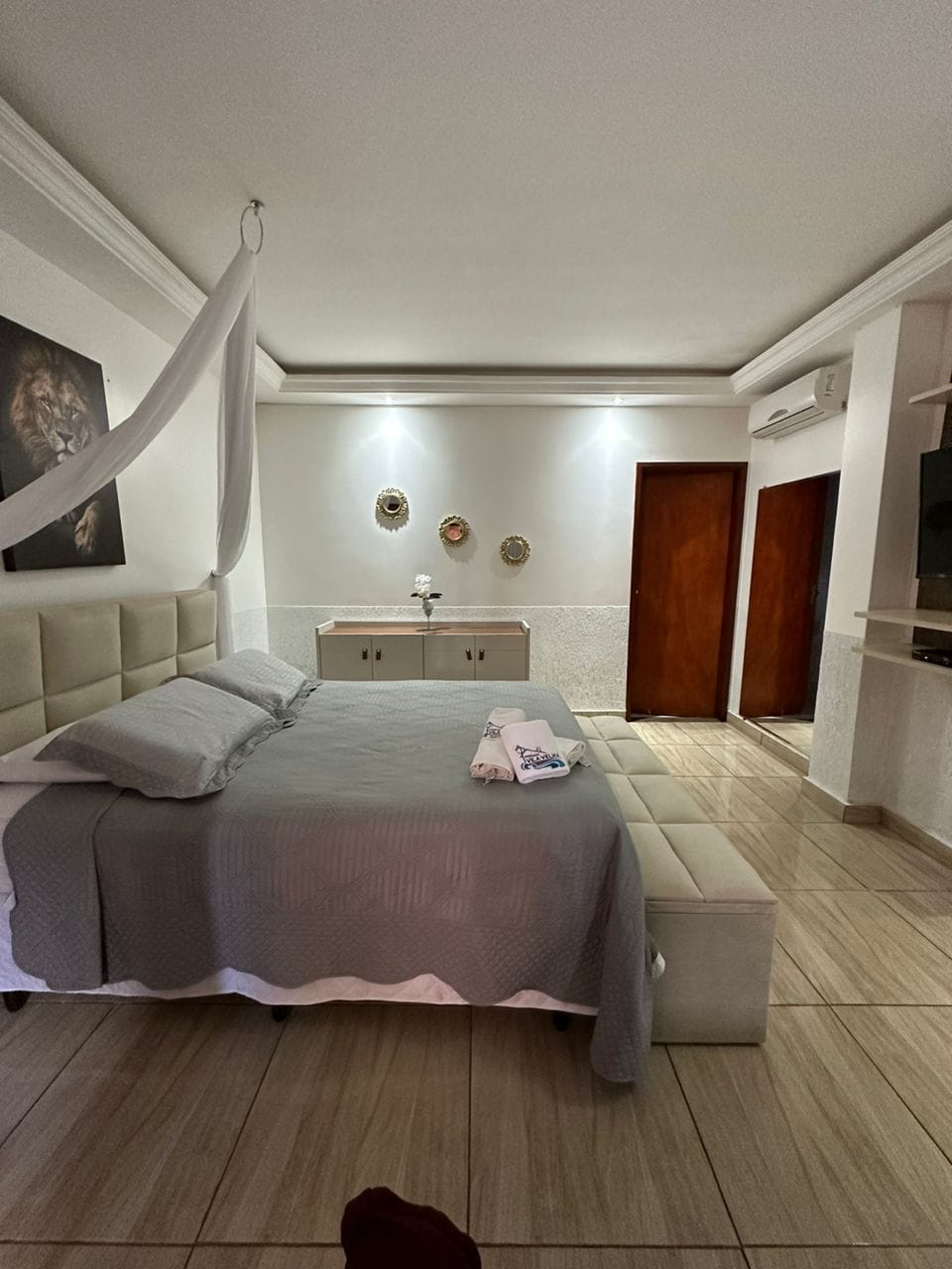Une chambre à coucher comprenant un lit, des tables de chevet, une armoire et un téléviseur.
