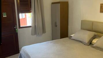 A hotel room with a bed, a wardrobe, a chandelier, and a window with curtains.