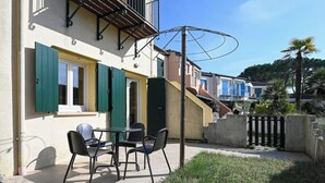 Ein Gebäude mit einer Terrasse, auf der sich ein Tisch und Stühle befinden, sowie eine Treppe und ein Zaun.