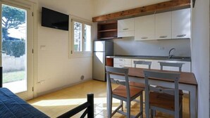 Eine kleine Küche mit weißen Schränken, einer Holz Arbeitsplatte und einem Fernseher über der Spüle.