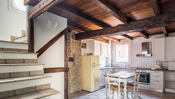 A kitchen with a central island, a dining table, and a staircase leading to another level. - Appartamento San Martino by Wonderful Italy (Bologna)