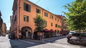 A street view with a building featuring arched windows and a red awning. - Appartamento San Martino by Wonderful Italy (Bologna)