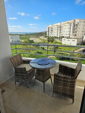 Enjoy a peaceful view from this balcony with a round table and two chairs.