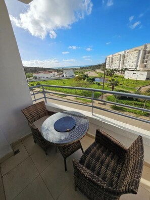 Enjoy a peaceful view from this balcony with a round table and two chairs.