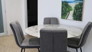 A round table with a marble top surrounded by four grey upholstered chairs. - Isla Verde Casa Azul (Isla Verde)