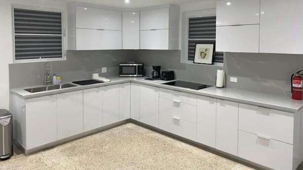 A modern kitchen with white cabinets, a stainless steel sink, a microwave, and a coffee maker. - Isla Verde Casa Azul (Isla Verde)