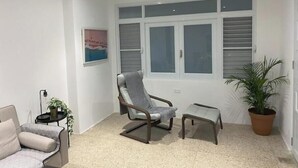 A modern living room with a sofa, a chair, a small table, and a potted plant. - Isla Verde Casa Azul (Isla Verde)