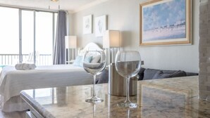Ein Hotelzimmer mit einem Bett, zwei Weingläsern, einer Kaffeemaschine und einem Gemälde an der Wand.