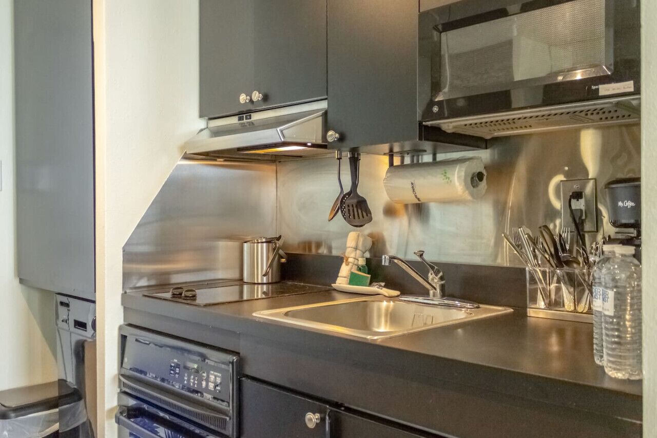 Una cocina moderna con electrodomésticos de acero inoxidable, un lavamanos y un microondas.