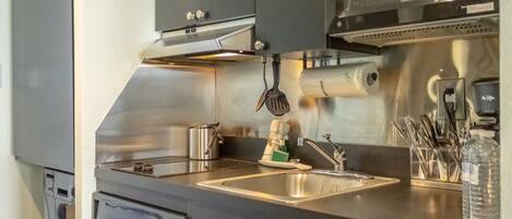 Una cocina moderna con electrodomésticos de acero inoxidable, un lavamanos y un microondas.