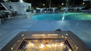 Un área de piscina con sillones de descanso y una chimenea.