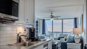 Una cocina moderna con cafetera, un lavamanos y un amplio ventanal con vistas a un balcón.