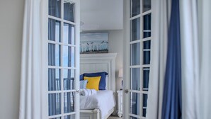 Un dormitorio con una cama, un cuadro de aves en la pared y vistas a través de un ventanal.