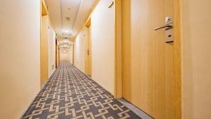 Un couloir d’hôtel avec des portes en bois et un tapis à motifs.