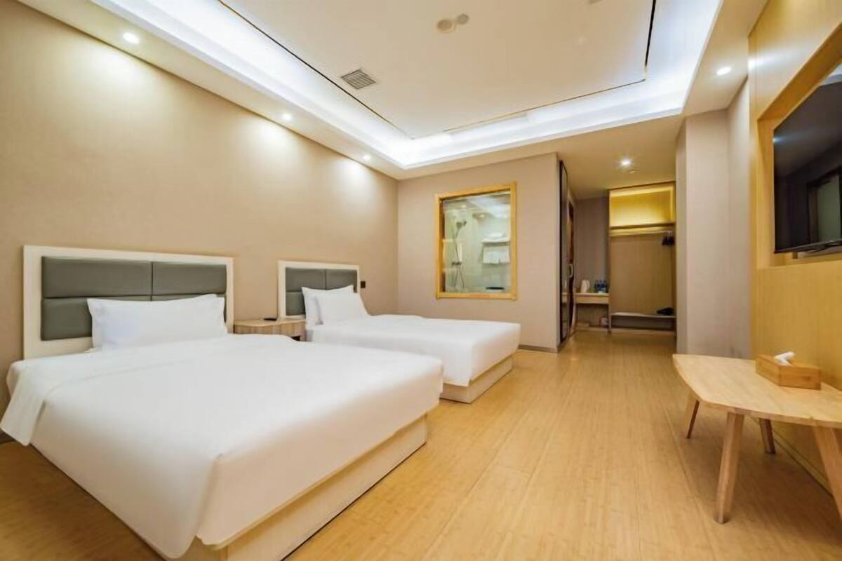 Ein Hotelzimmer mit zwei Betten, einem Schreibtisch und einem Spiegel.