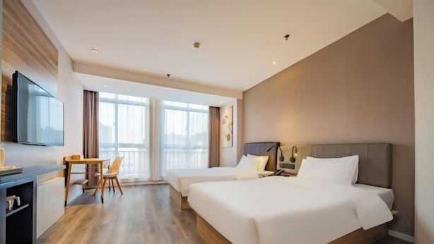Une chambre d’hôtel avec deux lits, un bureau, une chaise et un téléviseur.