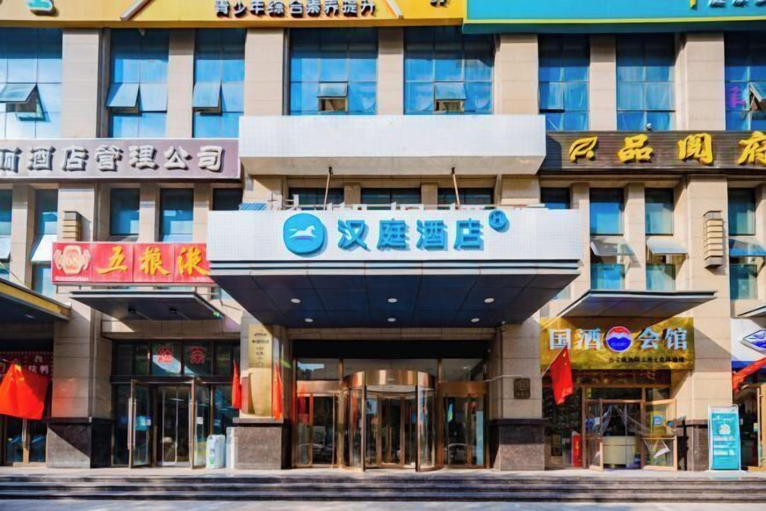 A hotel entrance with a revolving door, glass doors, and a sign above indicating it is a hotel.