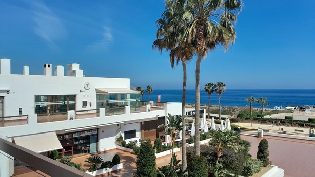 Ein modernes Hotel mit Dachterrasse, Blick auf das Meer, Palmen und einen angelegten Garten.