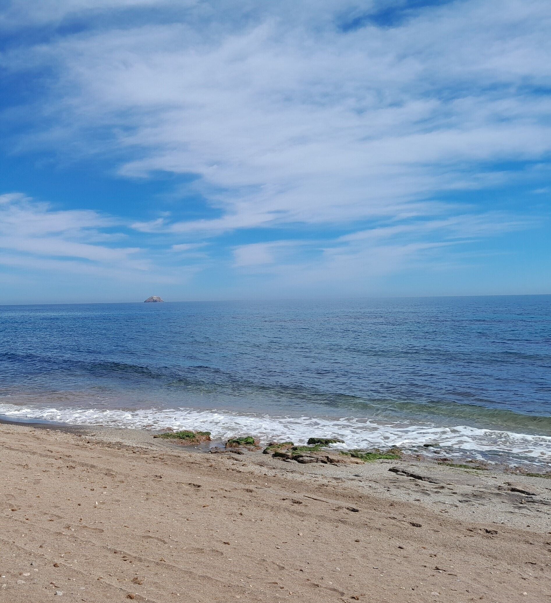 Una playa con cielos despejados y mar tranquilo.