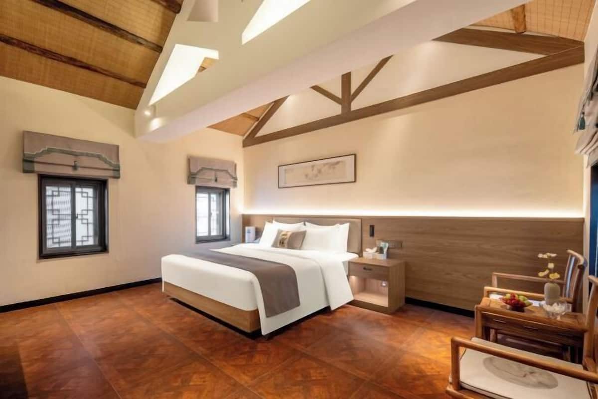 A bedroom with a large bed, bedside tables, a nightstand, and a wooden floor.