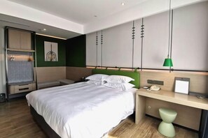 A modern hotel room with a large bed, a desk with a telephone, and a green pendant light. - Zhouchun Hotel (Zibo)