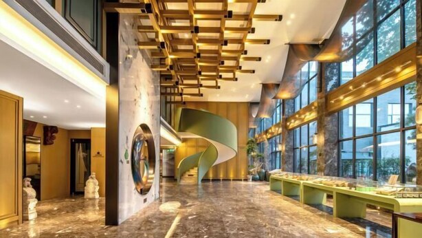 A spacious lobby with a marble floor, a curved wall feature, and a display case with items. - Zhouchun Hotel (Zibo)