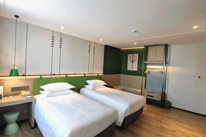 A hotel room with two beds, a desk, a green accent wall, and a small bathroom. - Zhouchun Hotel (Zibo)