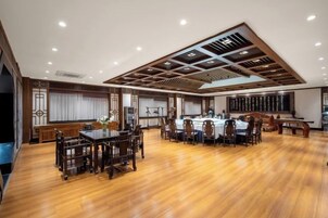 Una habitación amplia con piso de madera, una zona de comedor con mesas y sillas, y una cocina con encimera y electrodomésticos.