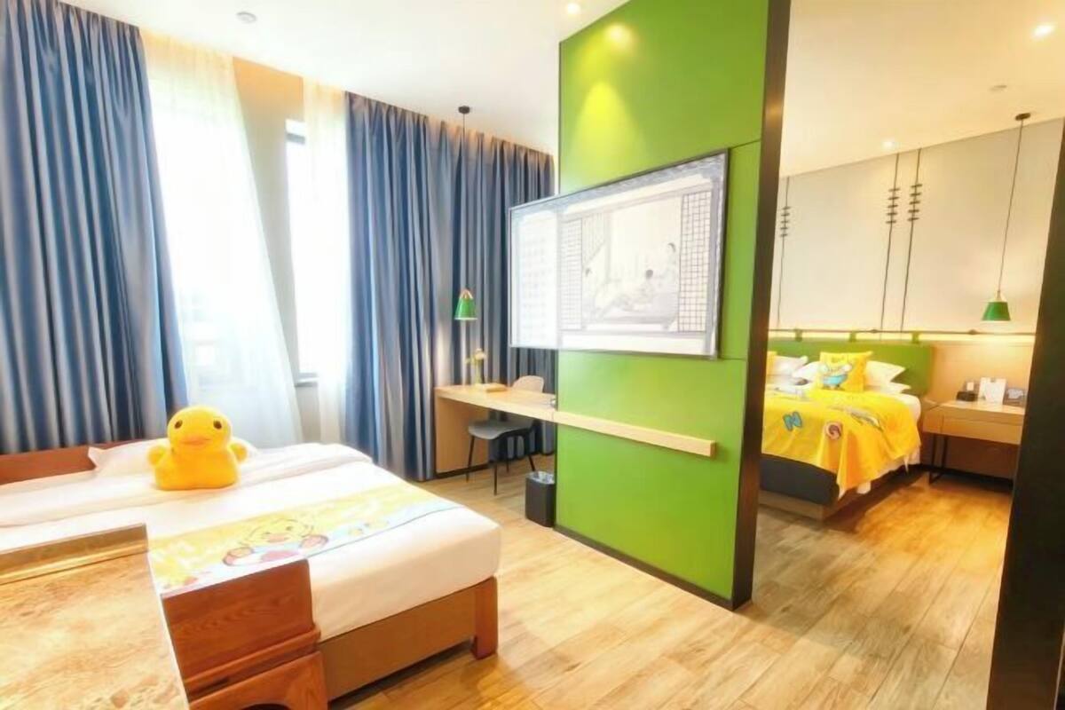 A hotel room with a bed, a desk, a chair, a TV, and a wardrobe.