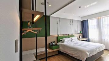 Quarto de hotel moderno com cama, mesas de cabeceira, uma parede verde e uma grande janela com cortinas.