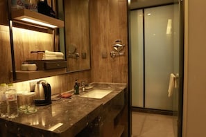 A modern bathroom with a marble countertop, a sink, a mirror, and a glass shower enclosure. - Zhouchun Hotel (Zibo)