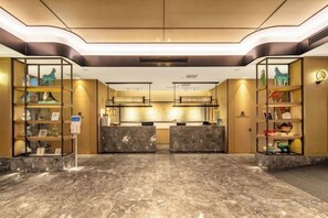 A hotel lobby with marble flooring, reception desks, and shelves with decorative items. - Zhouchun Hotel (Zibo)