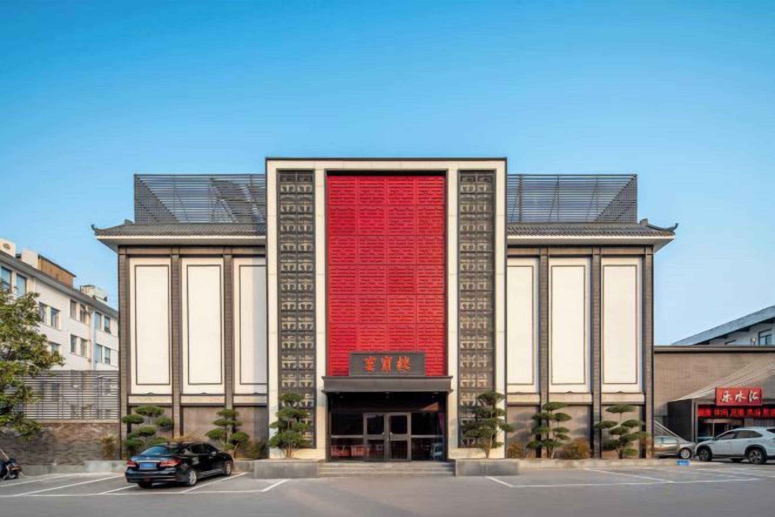 Un edificio con un llamativo muro rojo y un estilo arquitectónico tradicional.