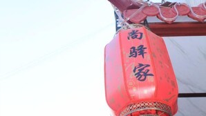 A red lantern with Chinese characters hanging from a building's roof.