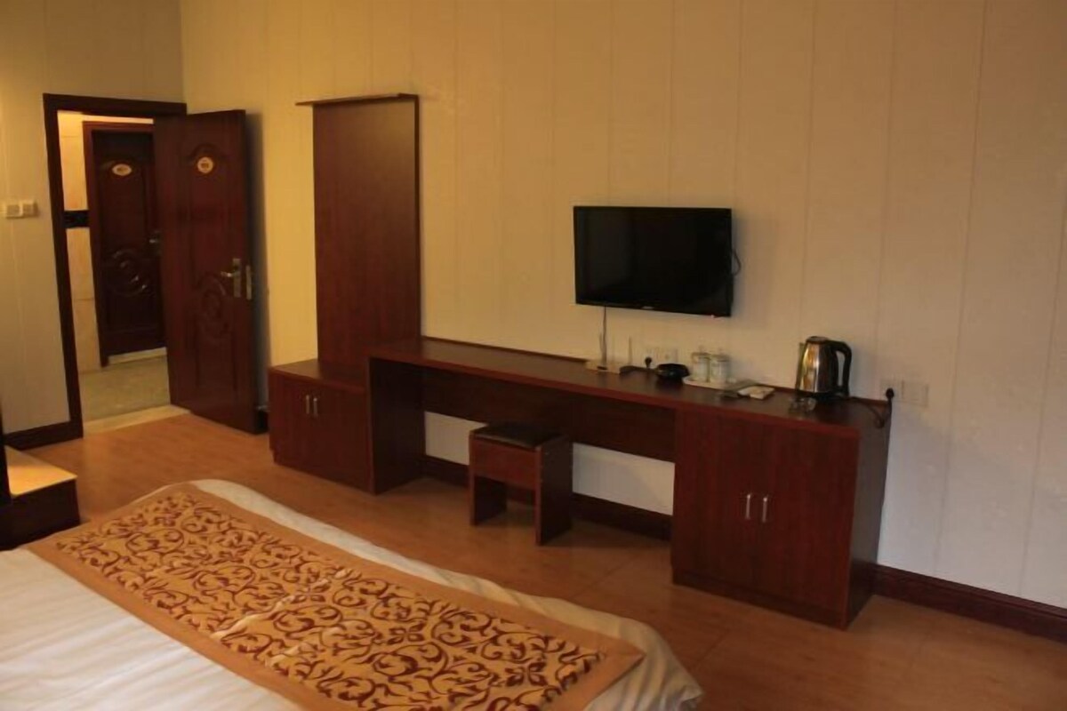 Een hotelkamer met een bed, een bureau, een televisie en een kledingkast.