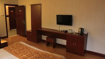 A hotel room with a bed, a desk, a television, and a wardrobe.