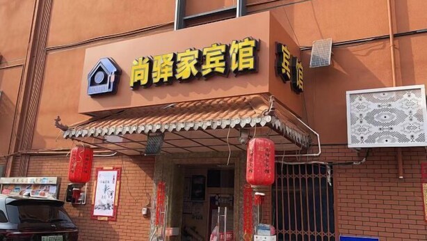 A building with a sign that reads "尚辉家宾馆" and a small house icon above the text.