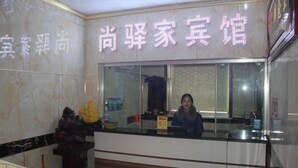 A hotel reception area with a marble wall and a neon sign.