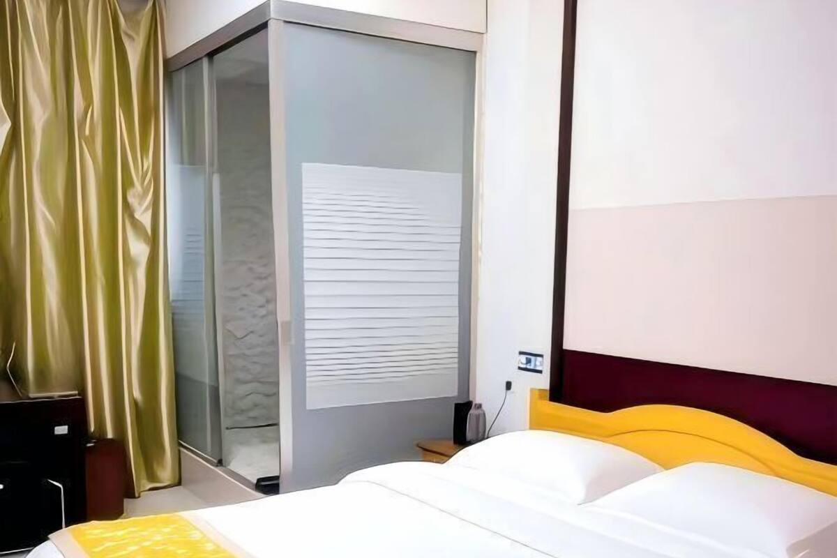 A hotel room with a bed, a wardrobe, a desk, and a curtain.
