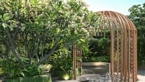 A garden with a wooden pergola, various plants, and a water feature. - Zenity Apartment Quan 1 (Ho Chi Minh City)