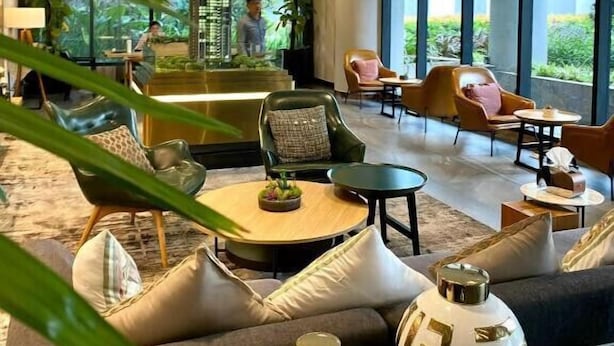 A spacious lobby with a modern design, featuring a seating area with sofas and chairs, a coffee table, and large windows offering a view of the outdoors. - Zenity Apartment Quan 1 (Ho Chi Minh City)