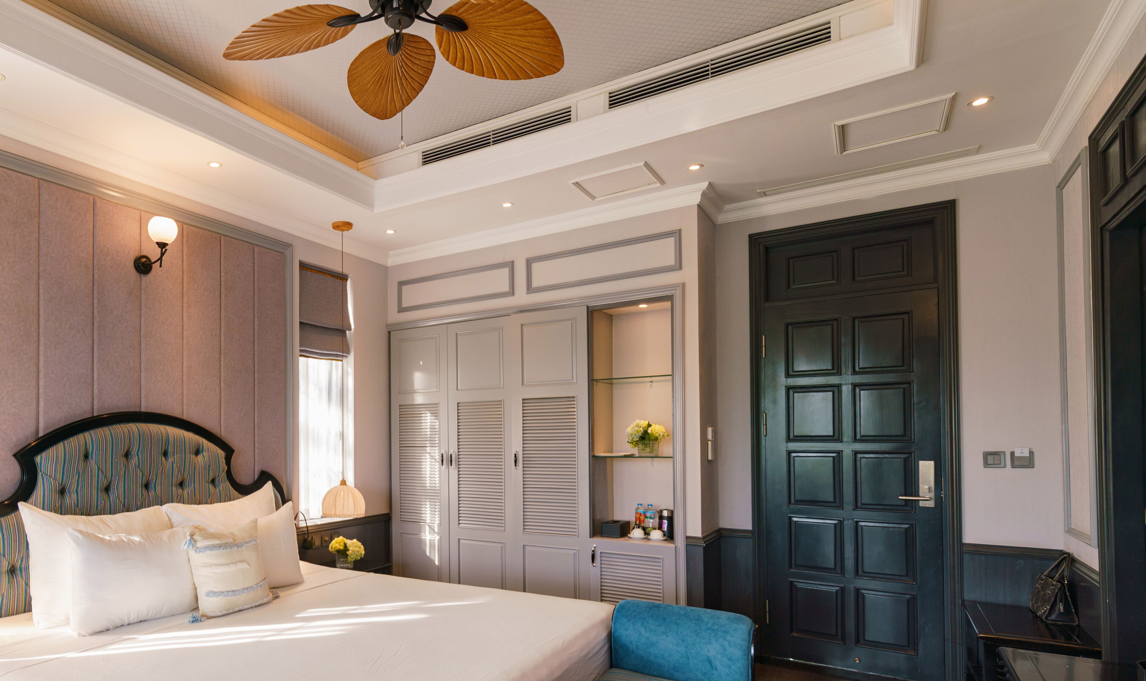 A hotel room with a bed, a desk, a wardrobe, and a door.