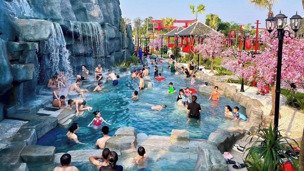 A public water park with multiple pools, a waterfall feature, and traditional-style structures.