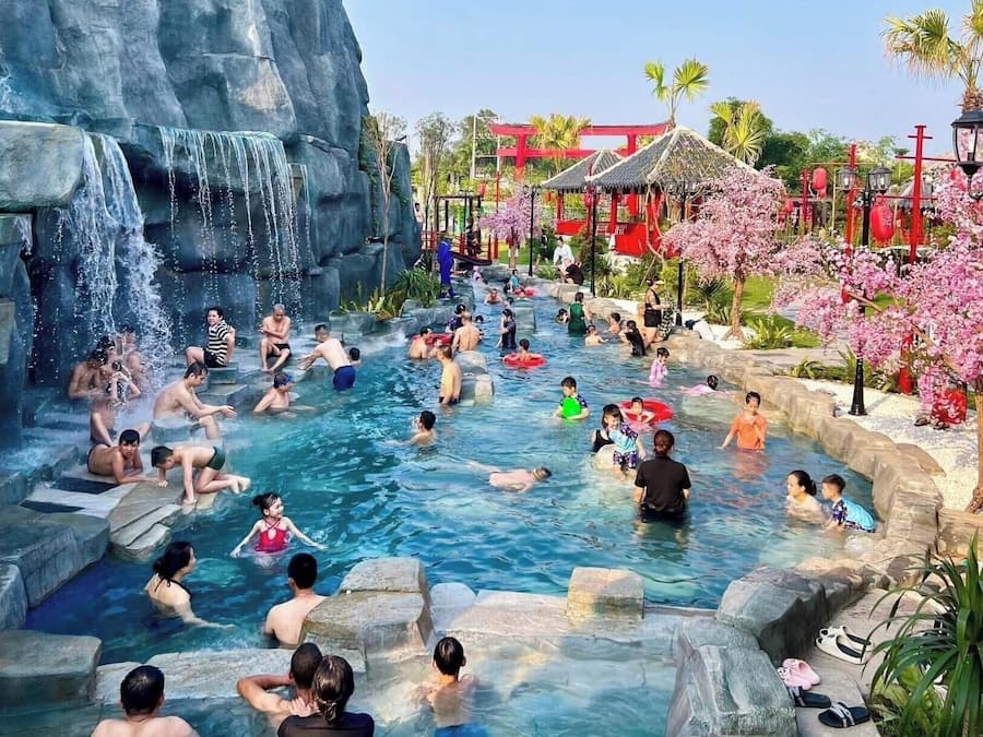 A public water park with multiple pools, a waterfall feature, and traditional-style structures.