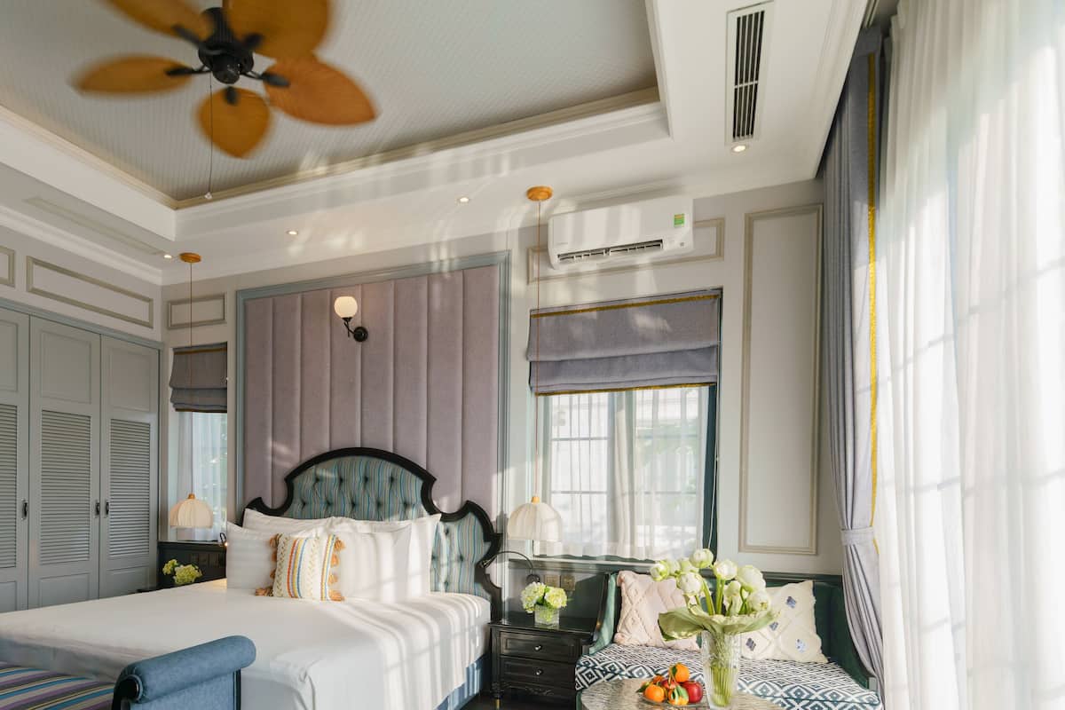 A bedroom with a large bed, a nightstand, a dresser, and a window with curtains.