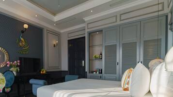 A hotel room with a large bed, a desk with a TV, a wardrobe, and a decorative wall.