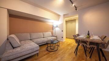 Una sala de estar moderna con un sofá modular, una mesa de centro redonda y una mesa de comedor lista para cuatro personas.