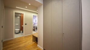 A hallway with wooden flooring, a white wardrobe, and a bathroom visible in the background. - Blloku Unique Apartments 2 (Tirana)