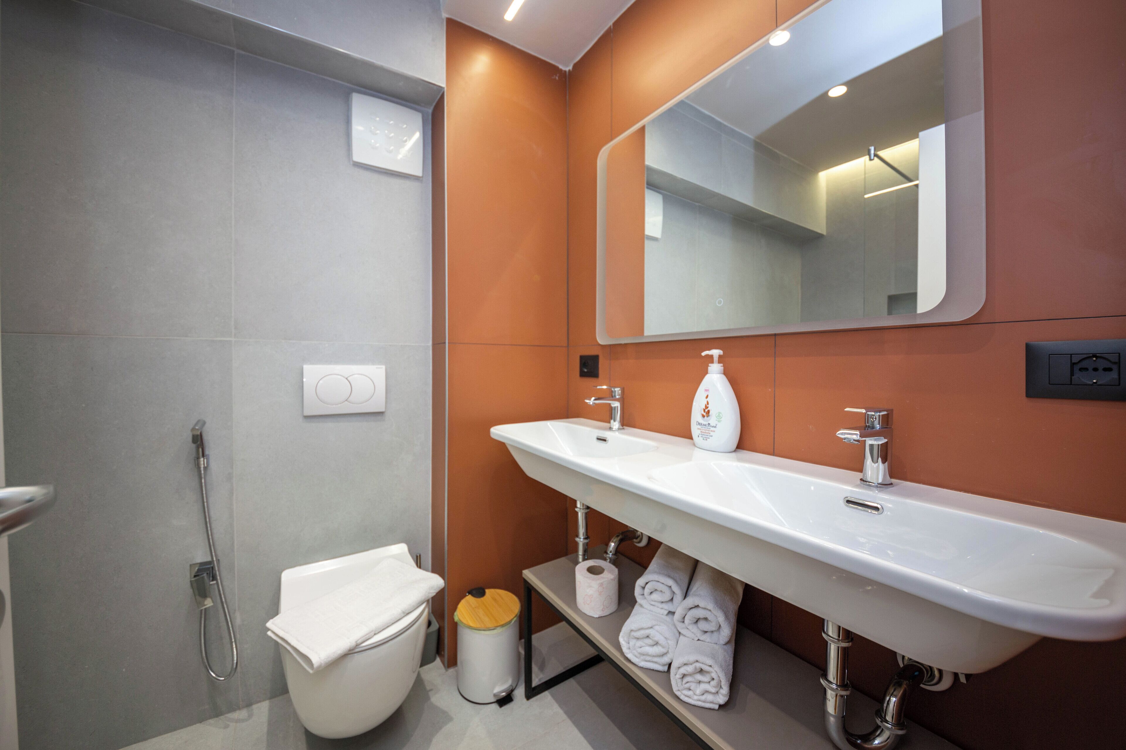 A modern bathroom with a white sink, a mirror, and a toilet.