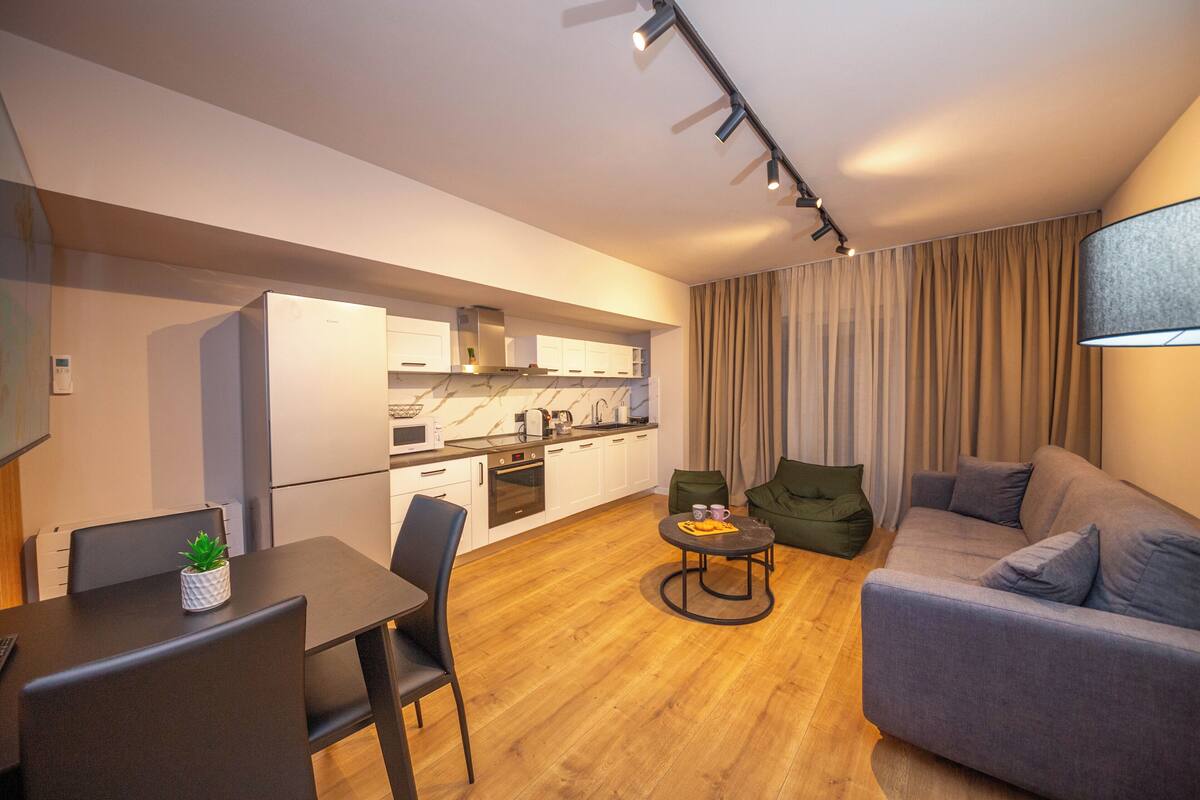 A modern living space with a dining area, kitchen, and seating area.